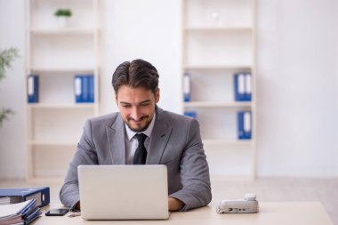 Genç işadamı işyerinde oturuyor.