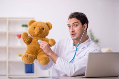 Genç doktor oyuncak ayı tutuyor.