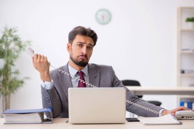 Genç işadamı işyerinde oturuyor.