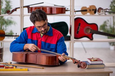 İçeride müzik aletlerini tamir eden genç bir adam.