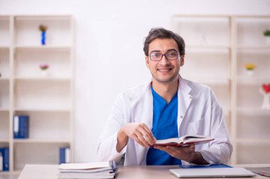 Hastanede kitap okuyan genç bir doktor.