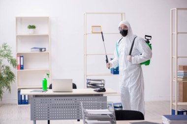 Young contractor disinfecting office during pandemic