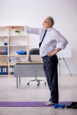 Eski erkek çalışanın teneffüste spor egzersizleri yapıyor.