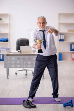 Eski erkek çalışanın teneffüste spor egzersizleri yapıyor.
