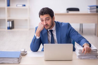 Genç işadamı ve işyerinde çok fazla iş var.