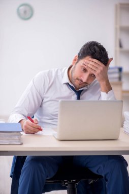 Genç işadamı ve işyerinde çok fazla iş var.