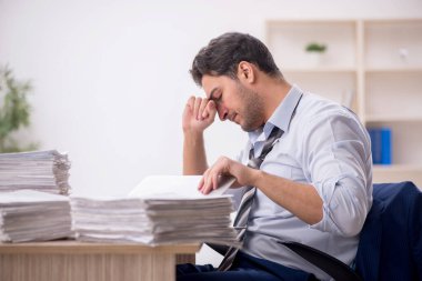 Young employee and too much work at workplace