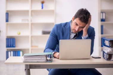 Genç işadamı ve işyerinde çok fazla iş var.