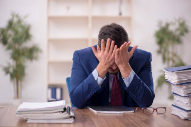 Young employee and too much work at workplace