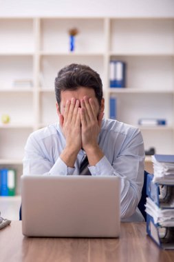 Genç işadamı ve işyerinde çok fazla iş var.