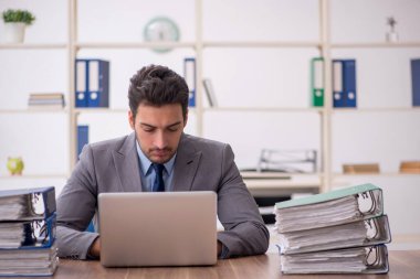 Young employee and too much work at workplace