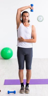 Genç yakışıklı adam içeride spor egzersizleri yapıyor.