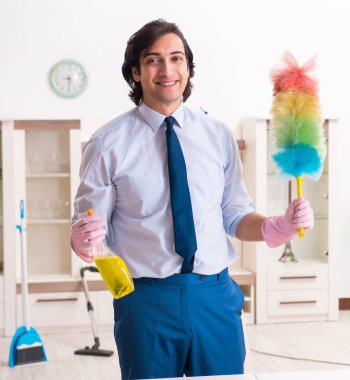 Genç işadamı evi temizliyor.