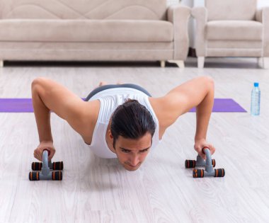 Genç adam evde antrenman ve egzersiz yapıyor.