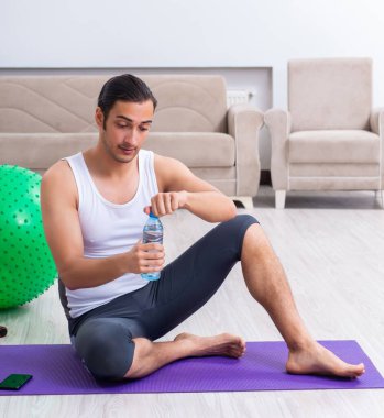 Genç adam evde antrenman ve egzersiz yapıyor.