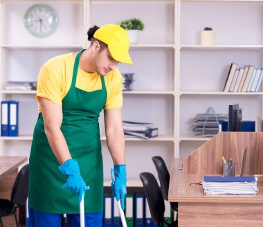 Genç erkek müteahhit ofisi temizliyor.