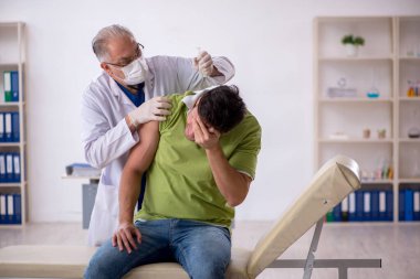 Genç hasta aşı konseptinde yaşlı doktoru ziyaret ediyor.