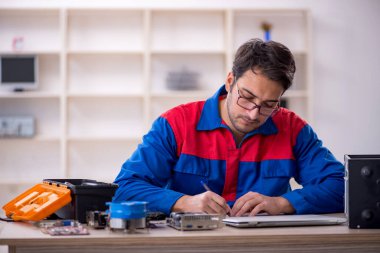 Atölyede bilgisayar tamir eden genç bir tamirci.