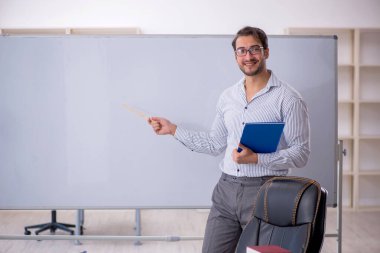 Genç öğretmen sınıfta oturuyor.