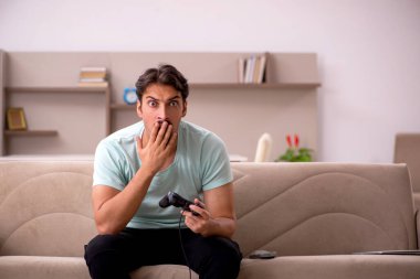 Evde oyun oynayan genç bir erkek öğrenci.