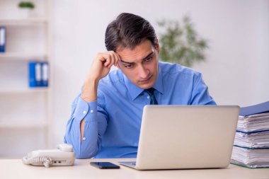 Genç işadamı ve işyerinde çok fazla iş var.