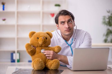 Genç doktor oyuncak ayı tutuyor.