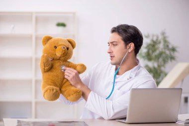 Genç doktor oyuncak ayı tutuyor.