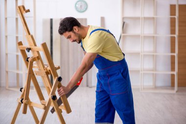 Atölyede sehpayı tamir eden genç bir tamirci.