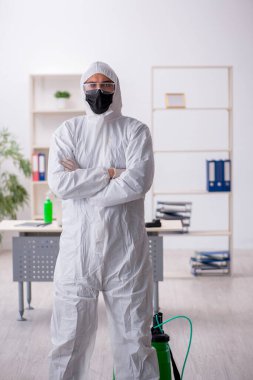 Young contractor disinfecting office during pandemic