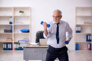 Eski erkek çalışanın teneffüste spor egzersizleri yapıyor.