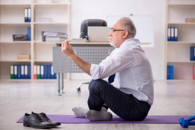 Eski erkek çalışanın teneffüste spor egzersizleri yapıyor.