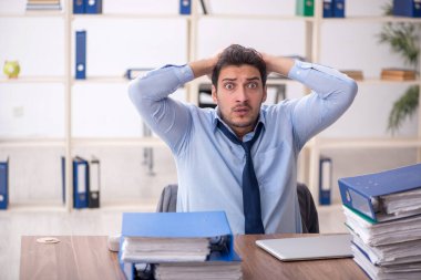 Young employee and too much work at workplace