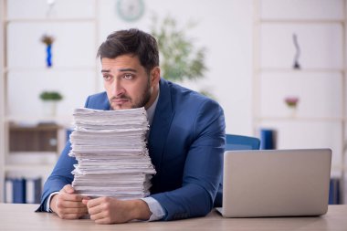 Genç bir çalışan ve ofiste çok fazla iş var.