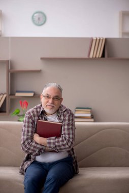 Old man reading book at home during pandemic