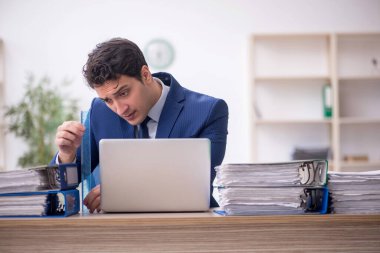 Genç işadamı ve işyerinde çok fazla iş var.