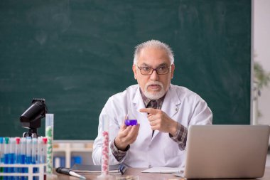 Old teacher chemist sitting in the classroom