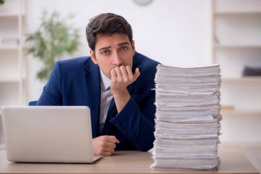 Young employee and too much work at workplace
