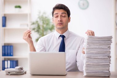 Young employee and too much work at workplace