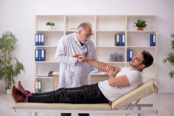 Young Doctor Visiting Old Doctor Chiropractor — Stock fotografie