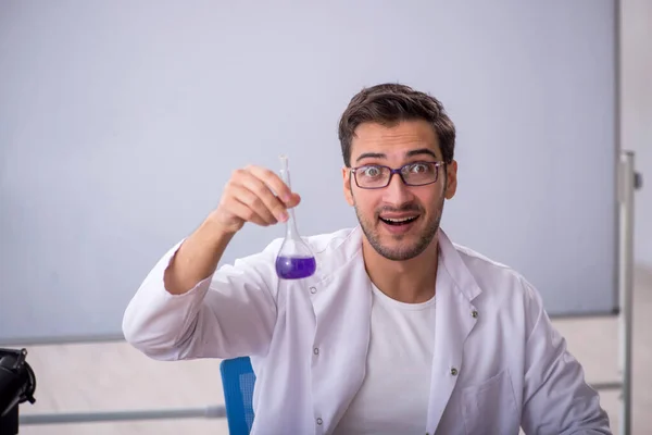 Young chemist in front of white board