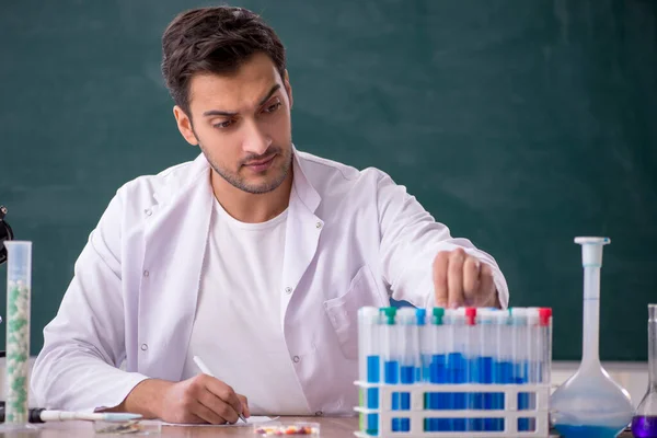 Young chemist in front of green board