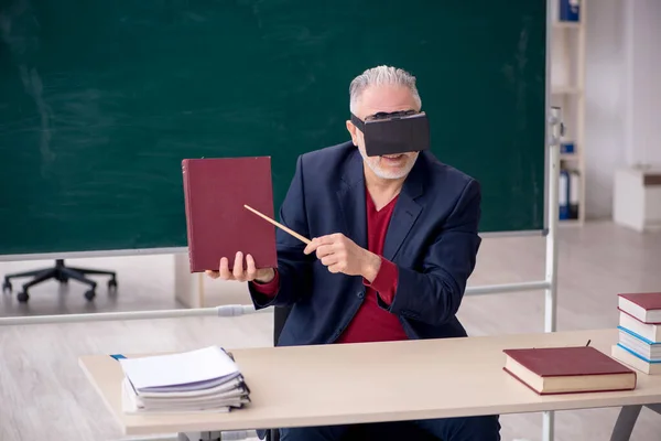 Old teacher wearing virtual glasses in the classroom