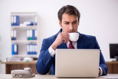 Genç işadamı teneffüste kahve içiyor.