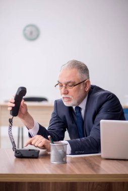 Old employee sitting at workplace