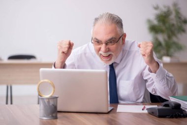 Old employee sitting at workplace