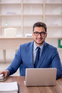 Genç işadamı işyerinde oturuyor.