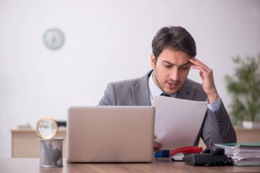 Genç erkek çalışan işyerinde oturuyor.