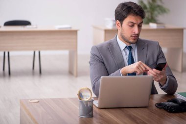 Genç erkek çalışan işyerinde oturuyor.