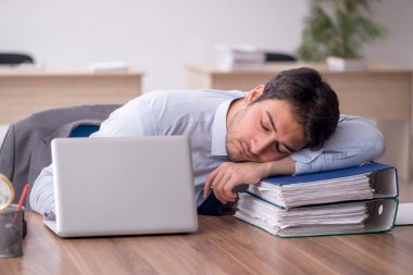 Genç erkek çalışan işyerinde oturuyor.