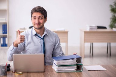 Genç erkek çalışan işyerinde oturuyor.